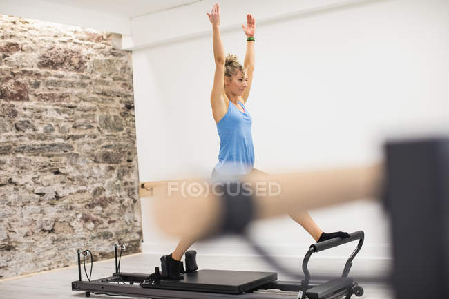 Woman exercising on reformer in fitness studio — Stock Photo
