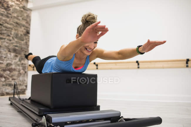 Mitte erwachsene Frau dehnt und trainiert auf Reformer im Fitnessstudio — Stockfoto