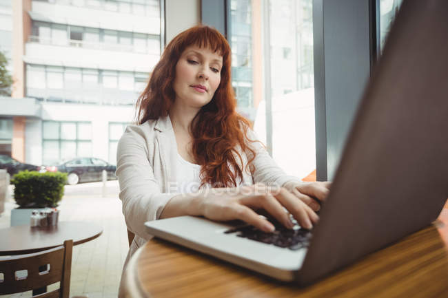 Femme d'affaires enceinte utilisant un ordinateur portable dans la cafétéria de bureau — Photo de stock