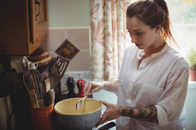 Femme debout et préparant le repas dans la cuisine à la maison — Photo de stock
