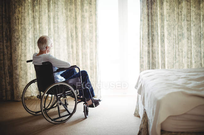 Homem idoso sentado em cadeira de rodas no quarto em casa — Fotografia de Stock