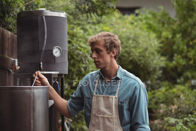 Man wearing apron making beer at home brewery — Stock Photo