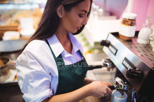 Garçonete tomando café da máquina de café expresso na cafetaria — Fotografia de Stock