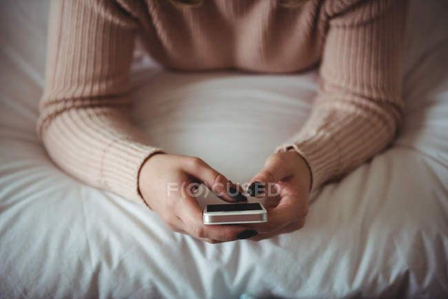 Розділ середині жінка, що використання мобільного телефону у спальні будинку — стокове фото