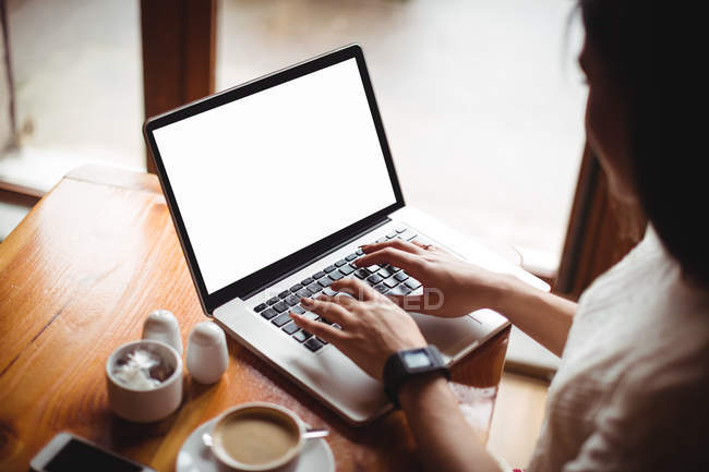 Mulher olhando tempo ao usar laptop no café — Fotografia de Stock