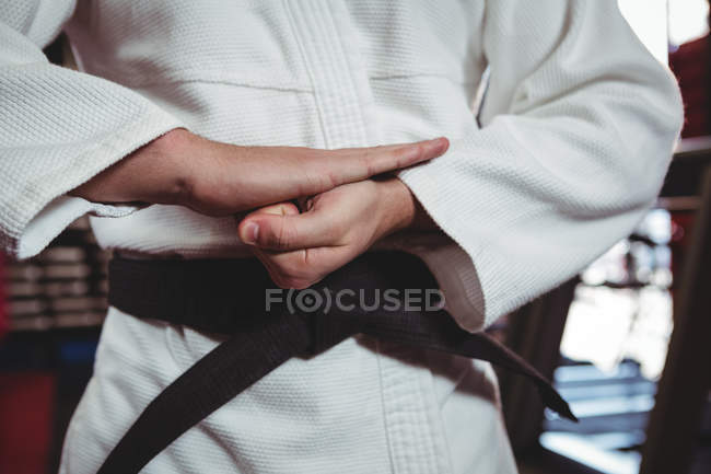 Sección media del jugador de karate que realiza postura de karate en el estudio de fitness - foto de stock
