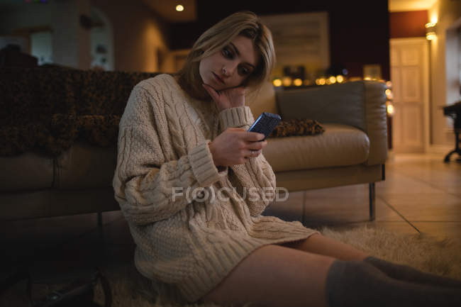 Donna che utilizza il telefono cellulare mentre seduto a casa — Foto stock