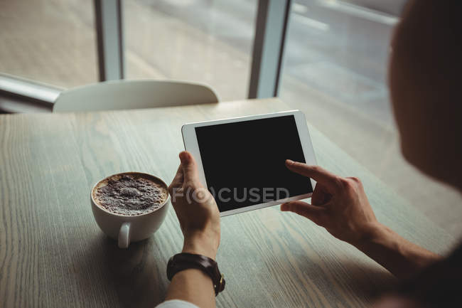 Mulher usando tablet digital enquanto toma uma xícara de café no café — Fotografia de Stock