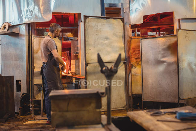 Glassblower heating glass in glassblowers oven at glassblowing factory — Stock Photo