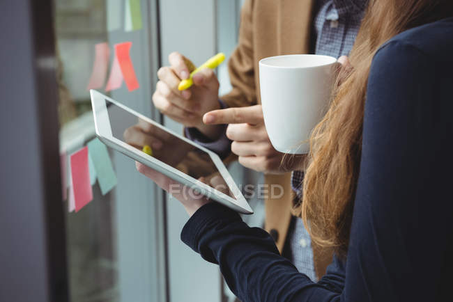 Керівники бізнесу обговорюють цифровий планшет, маючи чашку кави в офісі — стокове фото