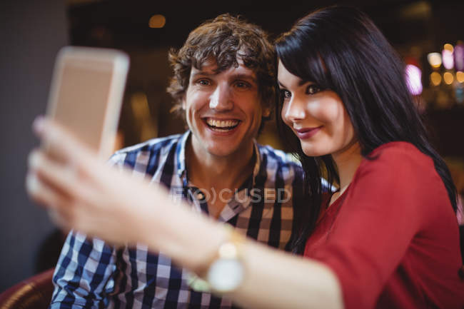 Casal tirando uma selfie usando telefone celular no restaurante — Fotografia de Stock