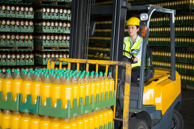Travailleuse confiante conduisant un chariot élévateur dans un entrepôt de distribution — Photo de stock