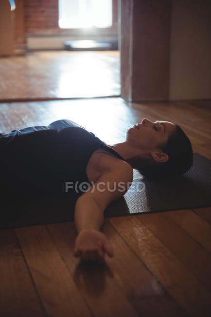 Жінка практикує йогу на килимку в фітнес-студії — стокове фото