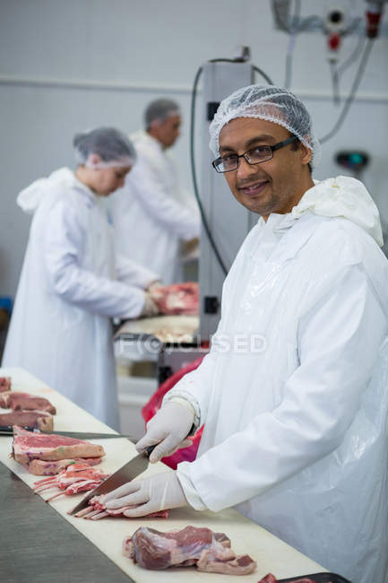 Retrato de açougueiro cortando carne na fábrica de carne — Fotografia de Stock