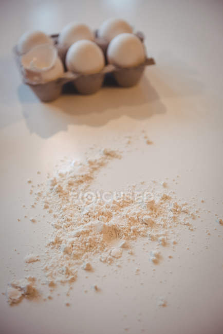 Ei im Karton und Mehl auf Küchenarbeitsplatte zu Hause — Stockfoto