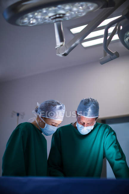 Cirurgiões masculinos e femininos realizando operação no teatro de operação do hospital — Fotografia de Stock