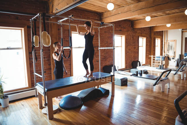 Trainer helping woman practicing pilates in fitness studio — Stock Photo