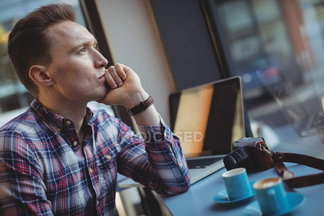 Thoughtful young man sitting in cafeteria — Stock Photo