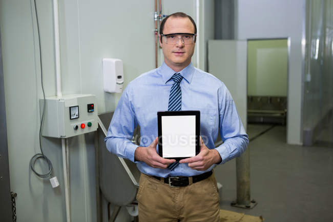 Técnico segurando tablet digital no interior da fábrica — Fotografia de Stock