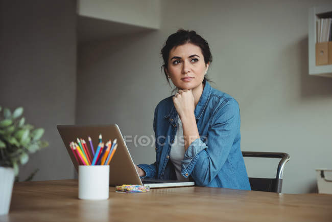 Thoughtful business executive using laptop in office — Stock Photo