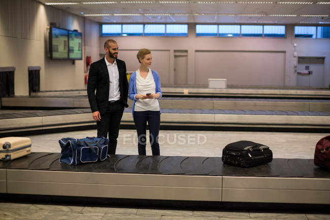 Coppia in attesa di bagagli nell'area ritiro bagagli in aeroporto — Foto stock