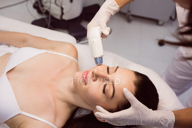 Dermatologo dare massaggio facciale al paziente attraverso soniclifting in clinica — Foto stock