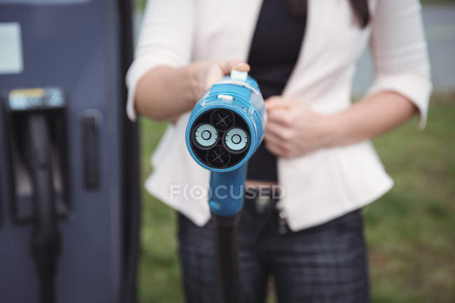 Mid section of woman holding car charger on street — Stock Photo