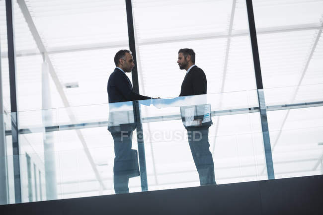Empresário cumprimentando um colega no corredor de um prédio de escritórios — Fotografia de Stock