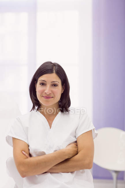 Портрет жінки-дерматолога, що стоїть на руках, схрещених у клініці — стокове фото