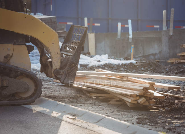 Bulldozer unloading timber at construction site — Stock Photo