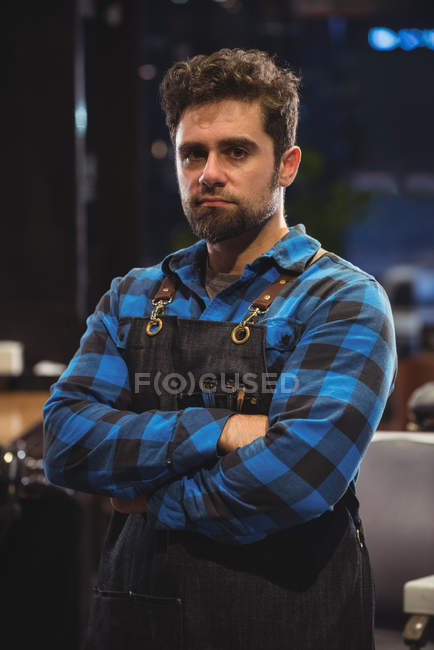 Front view of male barber standing with arms crossed in barber shop — Stock Photo