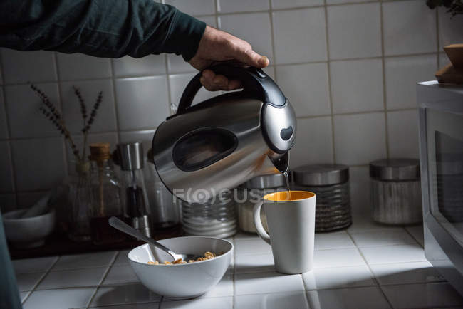 Uomo poring acqua calda da fiaschetta in cucina — Foto stock