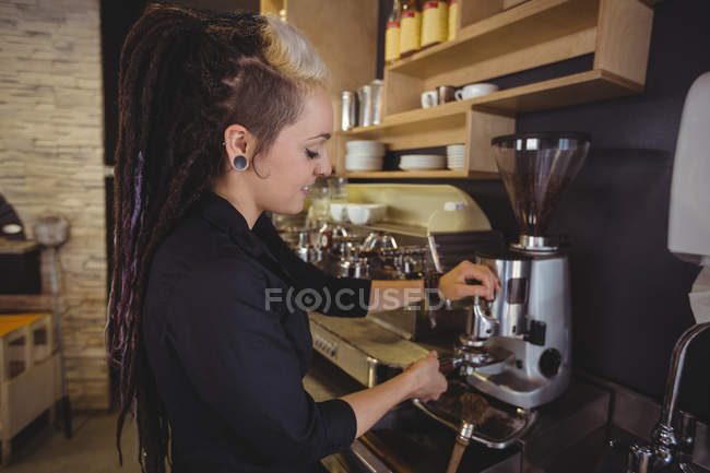 Camarera sosteniendo portafilter lleno de café molido en la cafetería - foto de stock