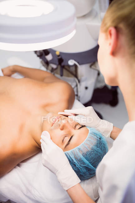 Arzt reinigt Gesicht des Patienten mit Gesichtsschwämmen in Klinik — Stockfoto