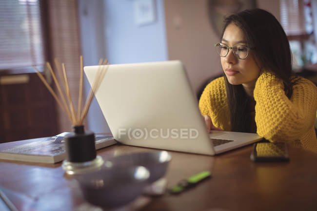Femme regardant ordinateur portable sur la table à la maison — Photo de stock