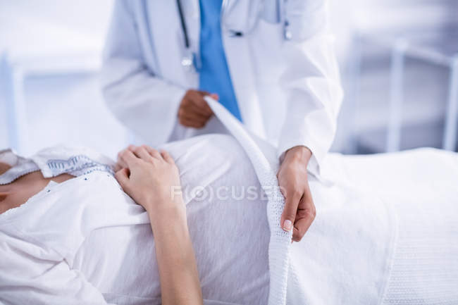 Середній відділ лікаря накидає ковдру на вагітну жінку в лікарні — стокове фото