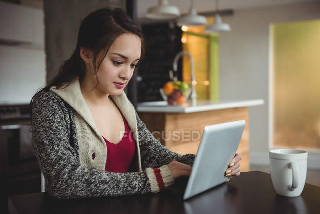 Жінка використовує цифровий планшет, маючи каву вдома — стокове фото