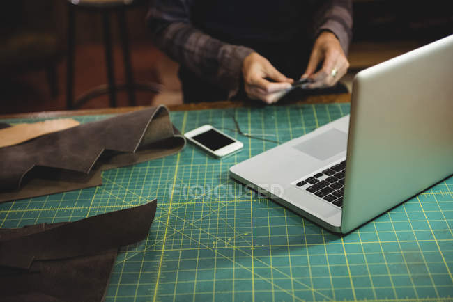 Мобільний телефон і ноутбук на столі в майстерні з майстрами на задньому плані — стокове фото