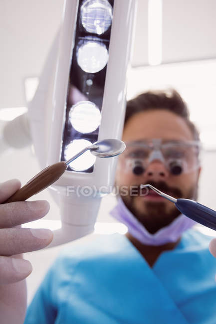 Primo piano del dentista che tiene gli strumenti dentali presso la clinica dentistica — Foto stock