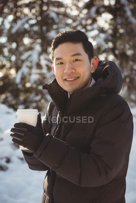 Портрет усміхненого чоловіка в теплому одязі, що тримає чашку кави взимку — стокове фото