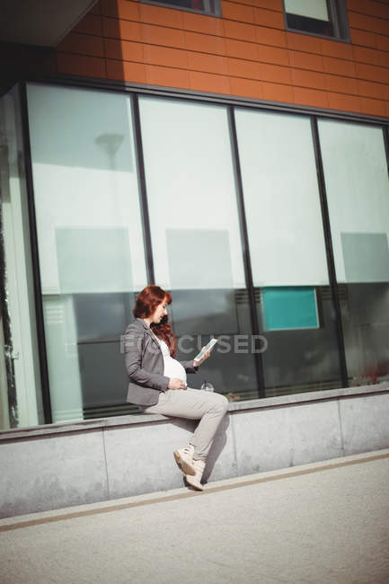 Femme d'affaires enceinte utilisant une tablette numérique dans des locaux de bureau — Photo de stock