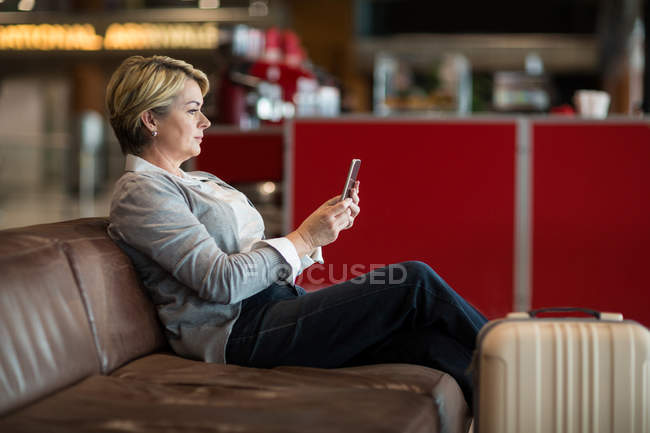 Geschäftsfrau benutzt Handy im Wartebereich am Flughafen-Terminal — Stockfoto