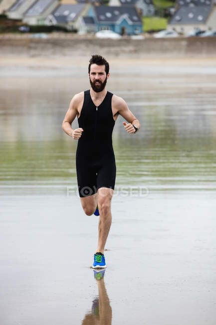 Hombre guapo corriendo en la playa - foto de stock