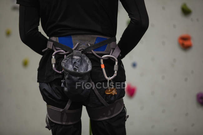 Mid section of man standing against artificial climbing wall in gym — Stock Photo