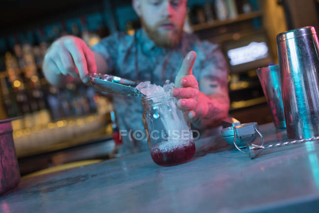 Barkeeper legt Eis ins Glas, während er Cocktails an der Bar zubereitet — Stockfoto