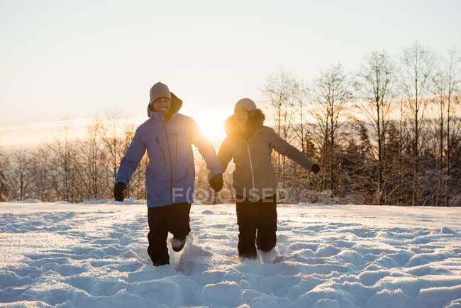 Happy couple walking on snow covered landscape — Stock Photo