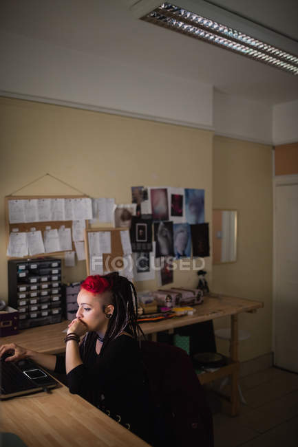 Female hairdresser using laptop in dreadlocks shop — Stock Photo