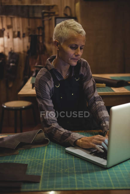 Artesana madura usando laptop en taller - foto de stock