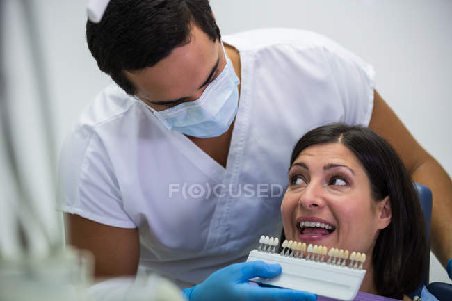 Дантист осматривает пациентку с оттенками зубов в стоматологической клинике — стоковое фото