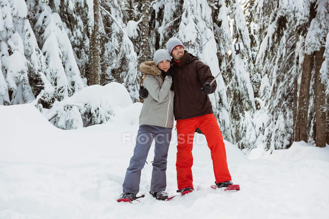 Feliz pareja de esquiadores tomando una selfie en la montaña cubierta de nieve - foto de stock
